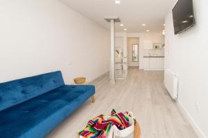 a living room with a blue couch and a kitchen at REFUGIO DEL PESCADOR Apartamento Maruca in Santander