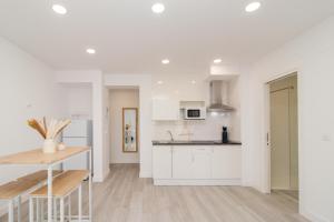 a kitchen with white cabinets and a wooden table at REFUGIO DEL PESCADOR Apartamento Maruca in Santander