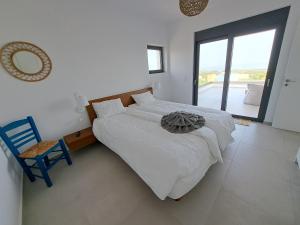 a bedroom with a bed and a chair and a window at Villa Milan 1 mit Padelplatz in Kos Town