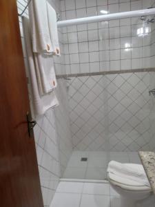 y baño con ducha, aseo y toallas. en Pousada Le Lieu, en Santo Antônio do Pinhal