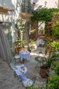 un patio con mesas blancas, sillas y plantas en Can Moio Turismo de Interior, en Montuiri