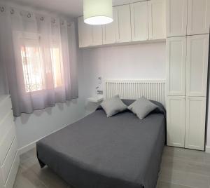 a bedroom with a bed and white cabinets and a window at Estudio Bajamar in Torre del Mar