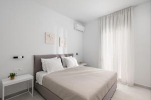 ein weißes Schlafzimmer mit einem großen Bett mit weißen Kissen in der Unterkunft The H Experience - Eclectic spacious apartment near Venetian Castle - 2 in Iraklio