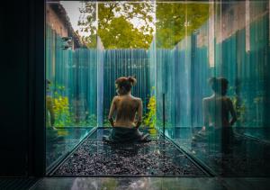 een vrouw die op een glazen vloer voor een fontein zit bij Les Cols Pavellons in Olot