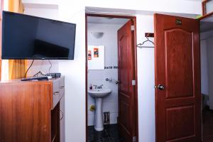 a bathroom with a tv and a sink and a toilet at Casa de Laura in Cusco