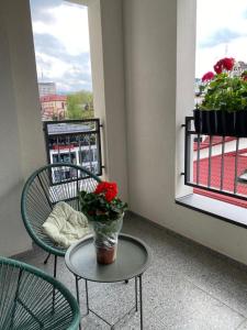einen Balkon mit 2 Stühlen und einem Tisch mit einer Blumenvase in der Unterkunft Апартаменты CLASSIC в жк Империал in Truskawez