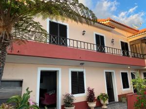 a white and red house with a balcony at Casa da Isilda ,three bedrooms in Estreito da Calheta