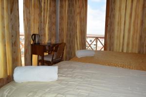 a bedroom with a bed and a desk and a window at Hotel Los Flamencos in Paracas