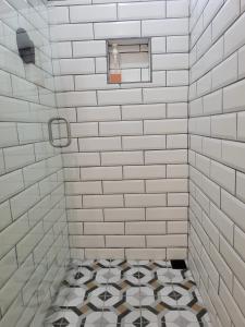 a white tiled shower with a black and white tile floor at Mecca in Puerto Viejo
