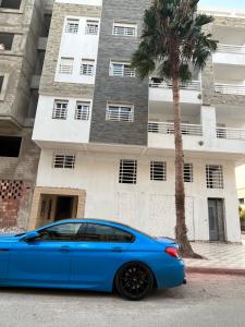 una macchina blu parcheggiata di fronte a un edificio di ABC Family appart a Saïdia