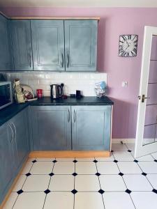 uma cozinha com armários azuis e uma parede rosa em The Grange em Admaston