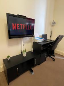 愛丁堡的住宿－Comfy 2 Bedroom Flat near Edinburgh City Center，办公室配有电视和带电脑的书桌
