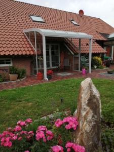 a house with a rock in the yard with pink flowers at Haus-Schiffer-Ferienwohnung-Finja in Rhauderfehn