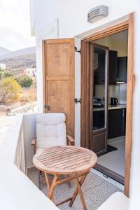 een kamer met een tafel en een stoel op een balkon bij Theoxenia Kasos Luxury Apartments in Panayía