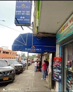 um grupo de pessoas em pé em um passeio em frente a edifícios em Hotel Plaza Calarcá em Calarcá