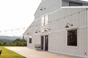 een wit huis met een veranda en een gebouw bij A Suite with a View + Wine in Mount Airy