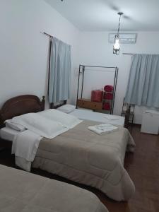 a bedroom with a bed with white sheets and a mirror at POUSADA PARLATORIUM in Tiradentes