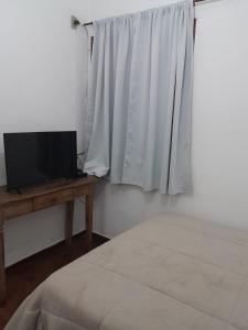 a bedroom with a bed and a television and a window at POUSADA PARLATORIUM in Tiradentes