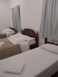 Duas camas num quarto com paredes brancas em POUSADA PARLATORIUM em Tiradentes