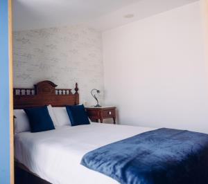 a bedroom with a white bed with blue pillows at Hotel Cueli in Viveda