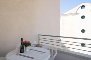 Una mesa blanca con botellas de vino y flores en un balcón. en Villa Jadì Sottomarina, en Chioggia