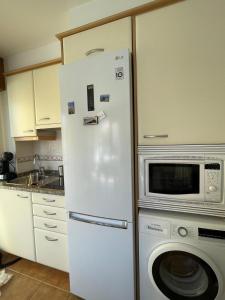 Un refrigerador blanco en una cocina con microondas. en Apartamento familiar en Finisterre playa Langosteira, en Finisterre 7 fotos más