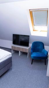een kamer met een tv en een blauwe stoel bij Bon Żur in Brzeg