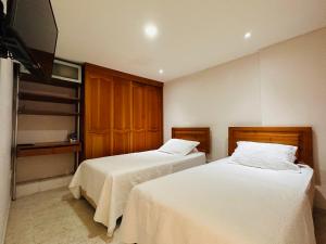 a bedroom with two beds and a flat screen tv at Apartamento Alvarez in Cartagena de Indias