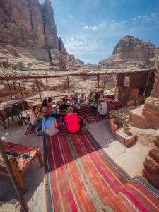 a group of people sitting on a rug in the desert at Indiana Jones Cave in ‘Ayn Amūn