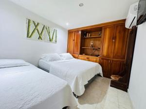 a bedroom with two beds and a wooden cabinet at Apartamento Alvarez in Cartagena de Indias