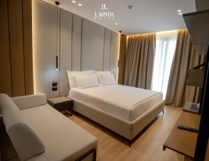 a bedroom with a large white bed and a couch at La Onda Hotel Durres in Durrës