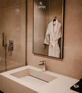 a bathroom sink with a white robe on a wall at La Onda Hotel Durres in Durrës