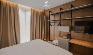 a bedroom with a bed and a tv and a window at La Onda Hotel Durres in Durrës
