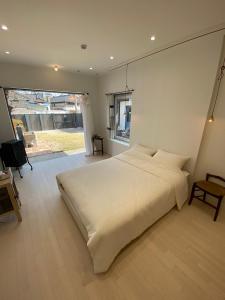 una camera da letto con un grande letto bianco e una finestra di Maison de Clare a Gyeongju