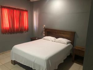 a bedroom with a white bed and a red window at Hotel Cambri in Nagua