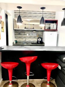 a kitchen with red stools in front of a counter at Flat em São Vicente com piscina na cobertura in Rio Grande da Serra