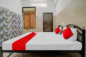 sypialnia z łóżkiem z białymi i czerwonymi poduszkami w obiekcie OYO Flagship Raj Hotel Near Juhu Beach w Bombaju