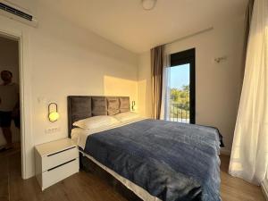 ein Schlafzimmer mit einem Bett und einem großen Fenster in der Unterkunft L house in Peani