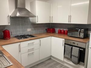 a kitchen with white cabinets and red appliances at 4 beds for 5 people beautiful apartment . in Plymouth