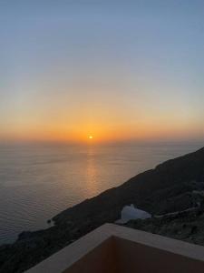a sunset over the ocean with the sun on a hill at Cactus villa in Karpathos Town