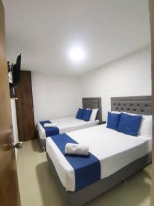 2 camas en una habitación con almohadas azules en Andaliving Campo Valdes Apartamento, en Medellín