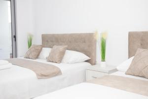 two beds in a bedroom with white walls at NESI Apartments in Ulcinj