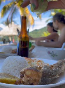 un plato de comida con arroz y una botella de cerveza en HOSTAL CRUZ DEL MAR, en Capurganá