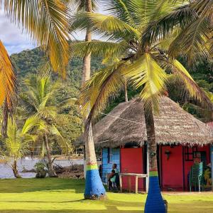 una pequeña cabaña con palmeras delante en HOSTAL CRUZ DEL MAR, en Capurganá