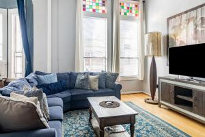 a living room with a blue couch and a tv at Greely Gaslamp - Loft W Parking & 3 Beds #202 in San Diego
