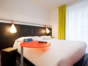 une chambre d'hôtel avec un lit et une table rouge dans l'établissement ibis Styles Paris République Le Marais, à Paris