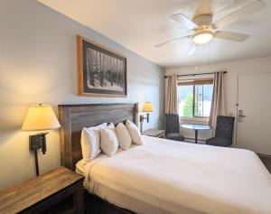 1 dormitorio con 1 cama blanca grande y ventilador de techo en Western Riviera Lakeside Lodging, en Grand Lake