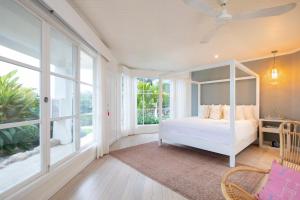 a bedroom with a white bed and large windows at The Retreat Costa Rica - Wellness Resort & Spa in Atenas