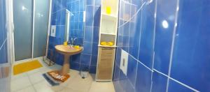 Baño de azulejos azules con lavabo y espejo en Vil'AJ, en Grand-Bourg