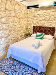 a bedroom with a white bed with a stone wall at Xcabal Hotel boutique in Bacalar